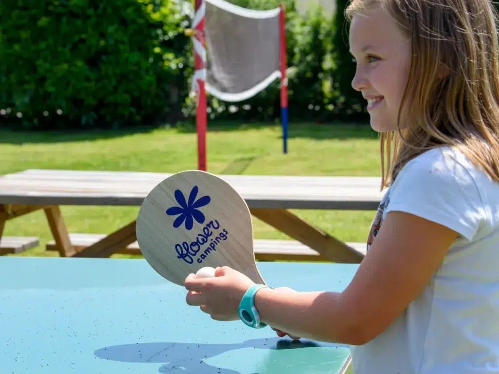 Enfant participant à une animation de jeux en plein air au camping Saint-Martin à Sorèze dans le Tarn, avec raquette personnalisée Flower Campings.