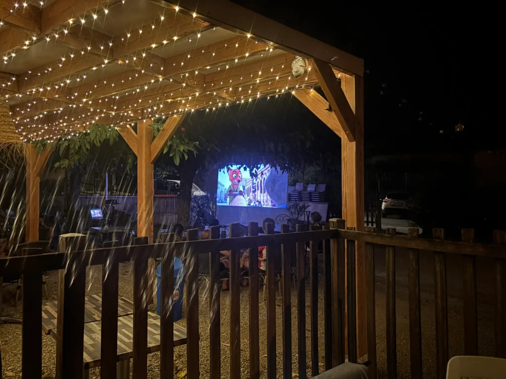 Animation cinéma en plein air au camping Saint-Martin dans le Tarn, avec écran géant et guirlandes lumineuses pour des soirées magiques en famille.