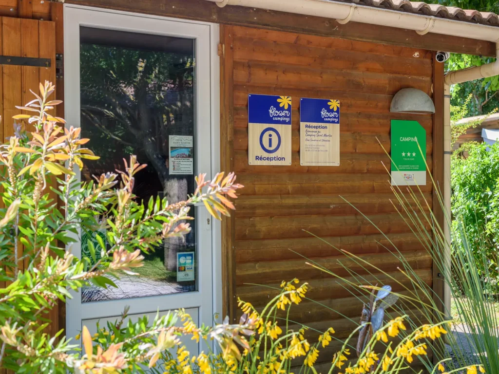 Bureau d'accueil du Flower Camping Saint Martin, proche de Castres dans le Tarn, avec signalétique et panneau d'informations. Un espace convivial pour un accueil personnalisé et des conseils pour vos vacances en camping.
