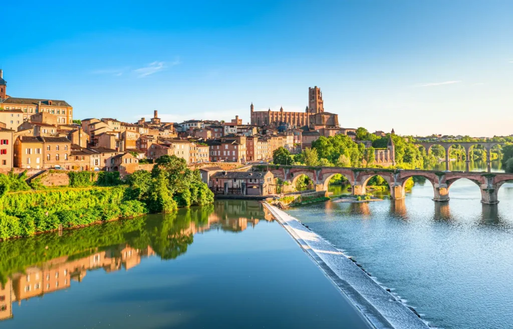 Vue panoramique de la cité d'Albi avec la cathédrale Sainte-Cécile et le pont sur le Tarn en Occitanie, reflétés dans les eaux calmes du Tarn.