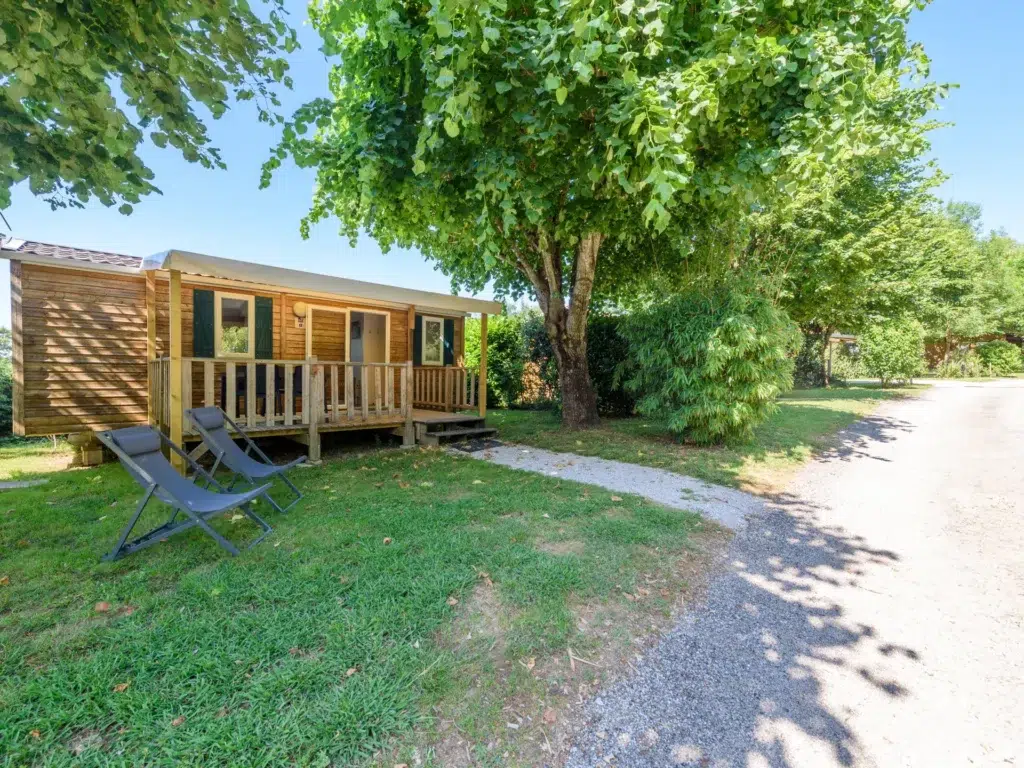 Mobil-home en cadre verdoyant proche de Toulouse, avec terrasse en bois et transats pour des vacances reposantes en pleine nature.