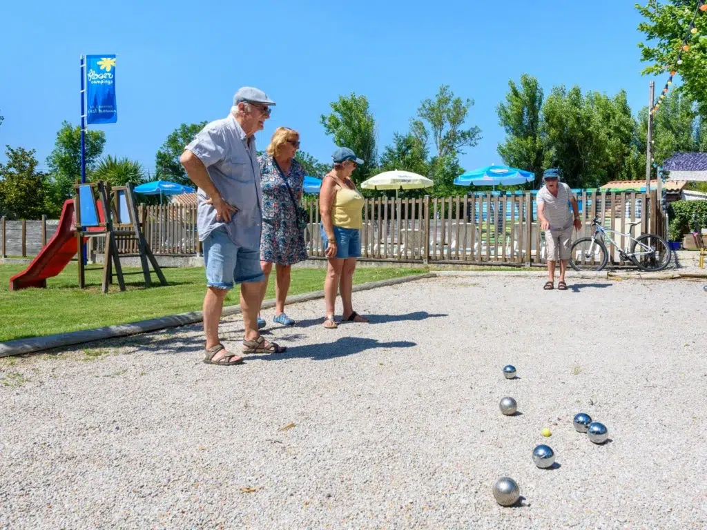 Famille jouant à la pétanque en pleine nature au camping Saint-Martin proche de Revel dans le Tarn, sous un ciel ensoleillé et entouré de verdure.