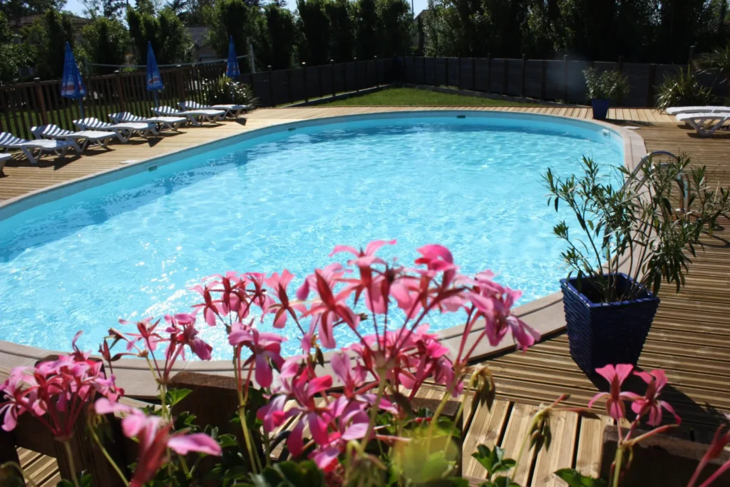 Piscine extérieure chauffée du camping familial Saint Martin à Sorèze, entourée d’une terrasse en bois, de transats et de plantes fleuries. Idéale pour des moments de détente en famille, proche d’Albi et de la Montagne Noire.