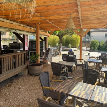 Snack-bar ombragé avec tables et chaises en osier, situé au bord de la piscine du camping Saint Martin à Sorèze, proche de Castres et de la Montagne Noire. Idéal pour des pauses détente en famille. Détendez-vous au snack-bar de notre camping, au bord de la piscine, et profitez d’une vue sur la nature environnante.