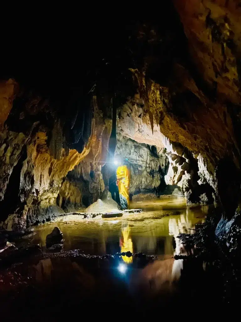 Spéléologue explorant une grotte souterraine lors d'une activité de spéléologie en pleine nature, organisée par le camping Saint-Martin dans le Tarn.