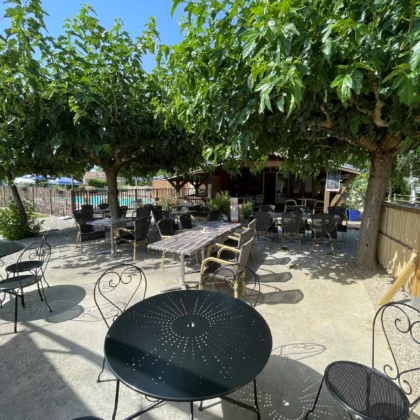 Terrasse ombragée du camping Saint Martin à Sorèze, avec tables et chaises pour des repas en plein air, proche de Revel et de la Montagne Noire. Profitez de notre terrasse ombragée pour des moments de détente en famille.