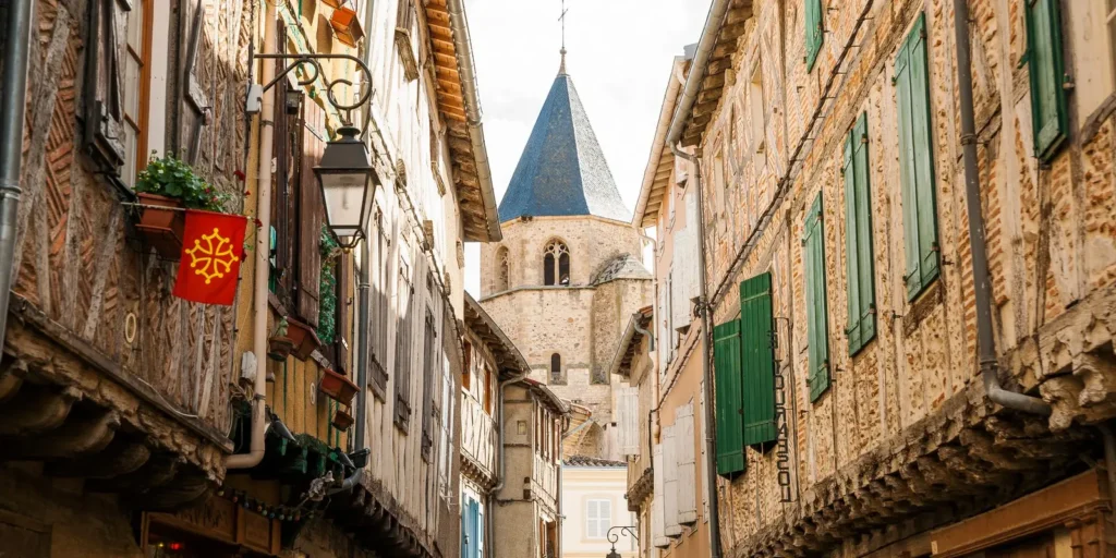 Rues pittoresques de la ville de Sorèze, proche du camping Saint Martin dans le Tarn, avec maisons à colombages et clocher historique. Idéal pour des balades culturelles et touristiques.
